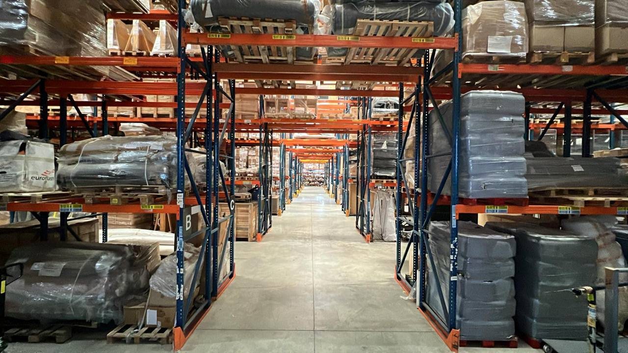Allée de racks et palettes filmées dans l'entrepôt MCE